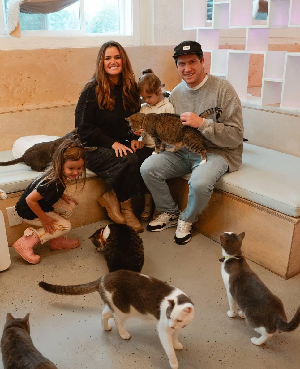 NEKO's founders, Caitlin & Cory, sit at NEKO Cat Cafe in Bellingham with their twin girls and six kitties roaming around them
